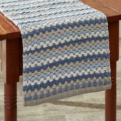 a blue and white table runner sitting on top of a wooden table next to a chair