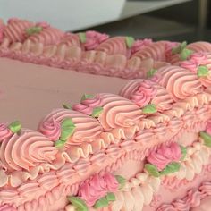 a large pink cake with green leaves on it's edges and frosting in the shape of a heart