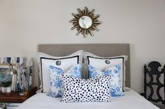 a white bed topped with lots of pillows next to a wall mounted sunburst