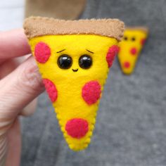 a hand holding a piece of felt pizza