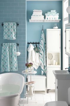 a white bath tub sitting next to a sink in a bathroom under a blue tiled wall