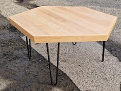 a small wooden table with hairpin legs on the ground next to an empty street