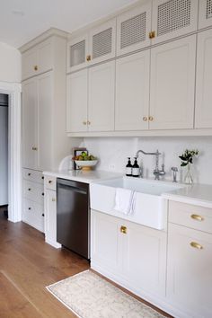 a clean kitchen with white cabinets and wood flooring, including a dishwasher