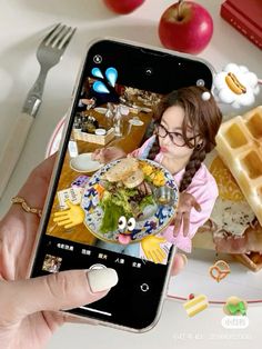 a person holding an iphone taking a photo of food on the table with waffles