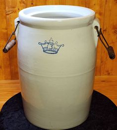 a large white bucket with a blue crown on the front and handle is sitting on a black mat