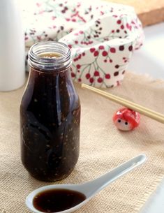 there is a jar of sauce next to a spoon on a table with other items