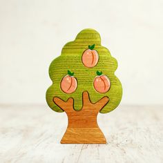 a wooden tree with apples on it sitting on a table