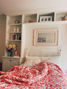 a bed with red and white bedspread in front of a book shelf filled with books