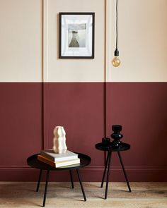 two small tables with books on them in front of a red and beige wall,