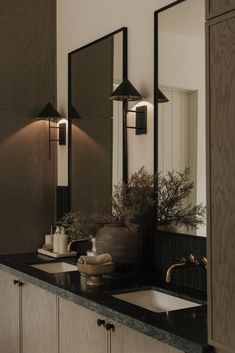 a bathroom with two sinks, mirrors and lights on the side of the wall above them