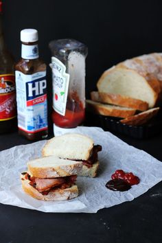 a sandwich sitting on top of a piece of wax paper next to condiments