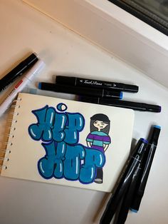 some markers and pens are laying on top of a notepad that has the word hip hop written on it