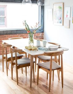 a dining room table and chairs in front of a brick wall