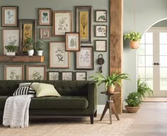 a living room filled with lots of framed pictures on the wall and green couches