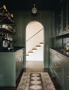 a kitchen with green cabinets and an area rug in front of the door that leads to another room