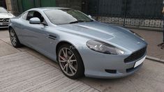 a blue sports car parked on the side of the road next to a man walking by