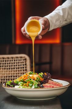 a person pouring sauce over a plate of food