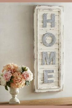 a vase filled with flowers sitting next to a sign that says home on the wall