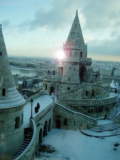 an old castle with snow on the ground and stairs leading up to it's top