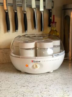 three jars are sitting on the counter in front of knives