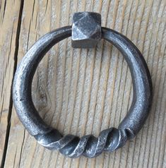 a close up of a metal ring on a wooden surface with a block of concrete in the middle