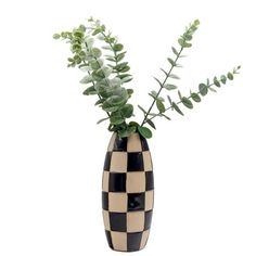 a black and white checkerboard vase with green plants in it on a white background