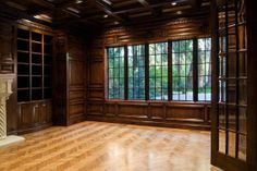 an empty room with wood paneling and large windows