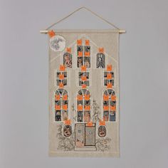 a white wall hanging with orange and black pictures on it's sides, along with an image of a house