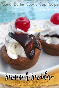 two cupcakes with whipped cream, cherries and chocolate on top are sitting on a plate next to the pool