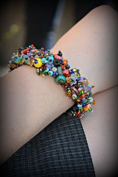 a close up of a person wearing a bracelet with colorful beads on the side of their arm