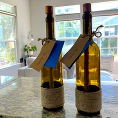 two wine bottles with tags attached to them sitting on a counter in front of a window