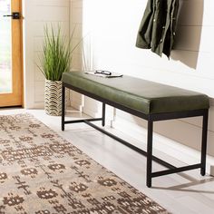 a bench sitting on top of a rug in front of a wooden door next to a green coat rack