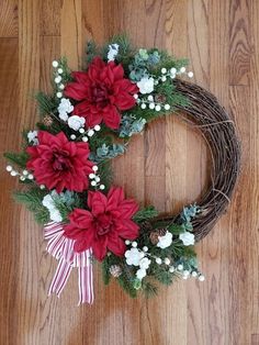 a wreath with poinsettis and greenery on a wooden floor