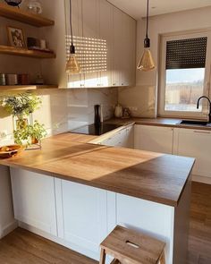 a kitchen with white cabinets and wooden counter tops, along with a small stool in front of the island