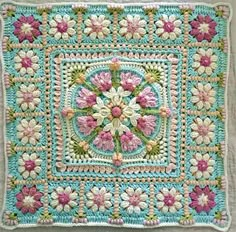 a crocheted square with pink and white flowers in the center on a blue background