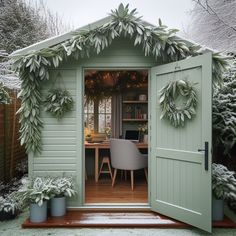 a green shed with potted plants on the front and side doors open to let in light