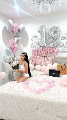 a woman sitting on top of a bed surrounded by balloons