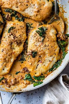 a pan filled with chicken and spinach covered in gravy on top of a table