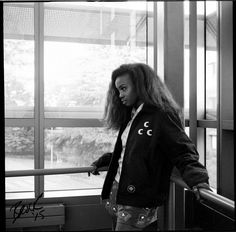 a woman standing next to a window near a railing