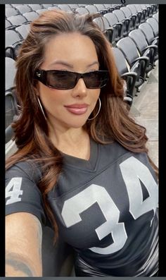 a woman wearing sunglasses is posing for a photo in front of an empty bleachers