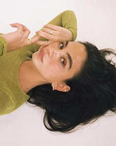 a woman laying on the ground with her hand up to her face and eyes closed