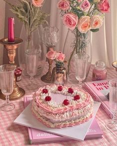 a heart shaped cake sitting on top of a table next to vases and candles