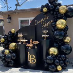 black and gold balloons are on display in front of a sign