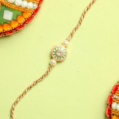 This year, on rakshabandhan, express your emotions and love with an exclusive Kundan rakhi for brother. Designed with a Kundan pendant of 1 inch, this elegant rakhi displays a round shape. It has a white stone at the center, surrounded by pink and green design. Off-white beads and beige threads complete the look of this rakhi. Order this elegant rakhi today. Kundan Rakhi, Rakhi For Brother, Purple Elephant, Handmade Rakhi, Pink Lotus, Raksha Bandhan, Indian Festivals, Gifts For Brother, Green Design