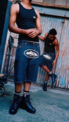 a man in black shirt and shorts standing next to another man with his hand on his hip