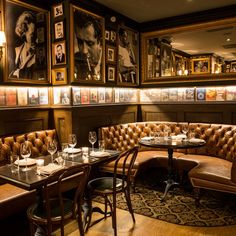 a restaurant with leather booths and pictures on the wall behind them, along with wine glasses