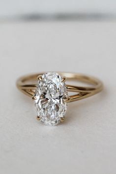 an oval cut diamond ring on a white surface