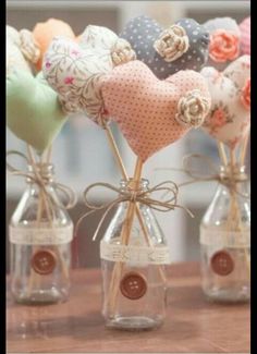 small glass vases with hearts in them are sitting on a wooden table and tied together