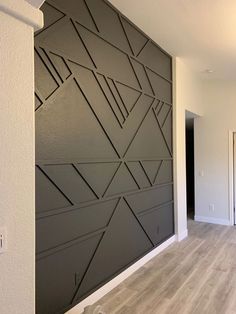 an empty room with wood flooring and a wall that has geometric designs on it