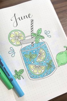 an open notebook with a drawing of a jar of lemonade on it and two markers